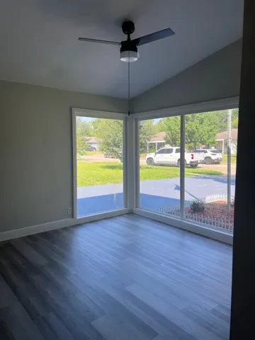 a view of an empty room with wooden floor and a window