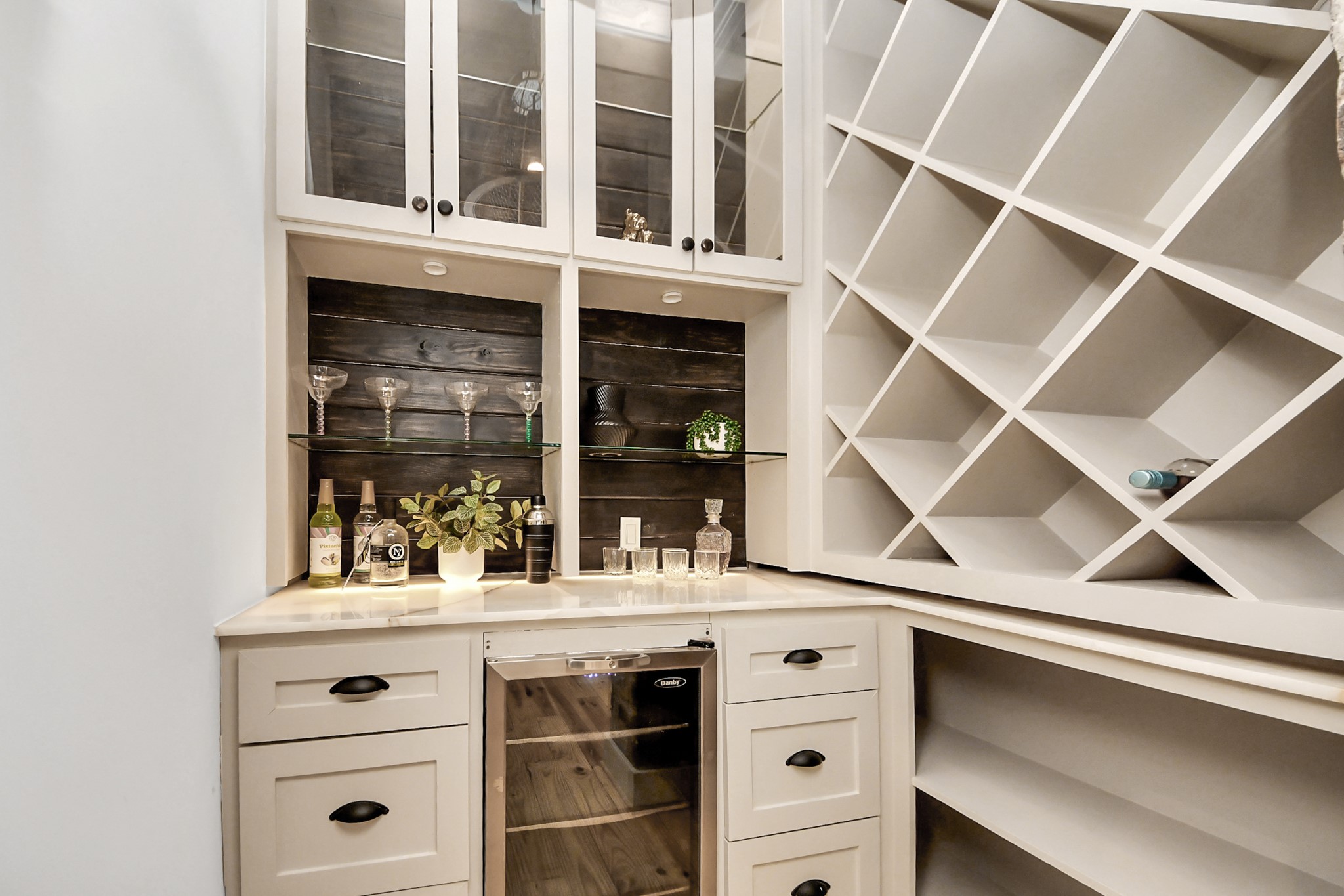 1202 Archer Street Houston, TX 77009 - Photo 17 of 46 This chic home bar blends modern design with practical functionality. Highlighted by a sleek wine rack, glass-front cabinets, and a built-in mini fridge, it provides ample storage while creating an inviting space perfect for entertaining in style.