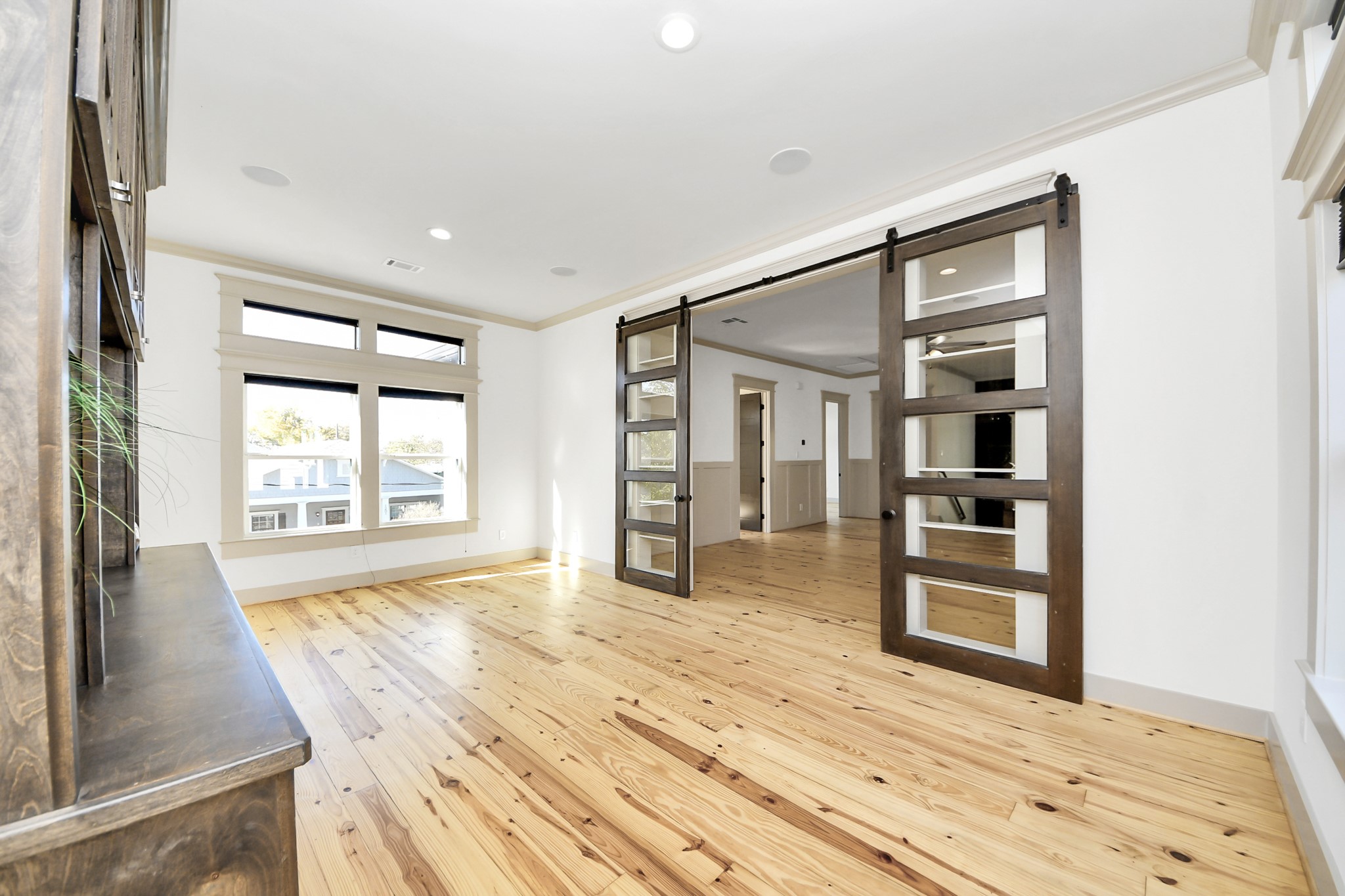 1202 Archer Street Houston, TX 77009 - Photo 34 of 46 This spacious, sun-filled room showcases beautiful hardwood floors and large windows that flood the space with natural light. Stylish sliding barn doors add both character and functionality, creating a modern yet inviting atmosphere.