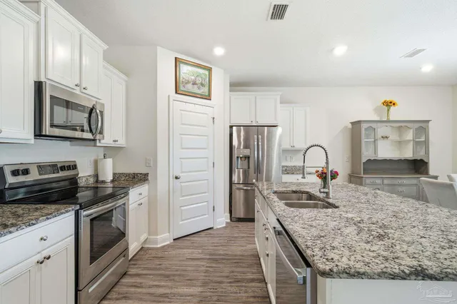 a kitchen with stainless steel appliances granite countertop a refrigerator a stove and a sink