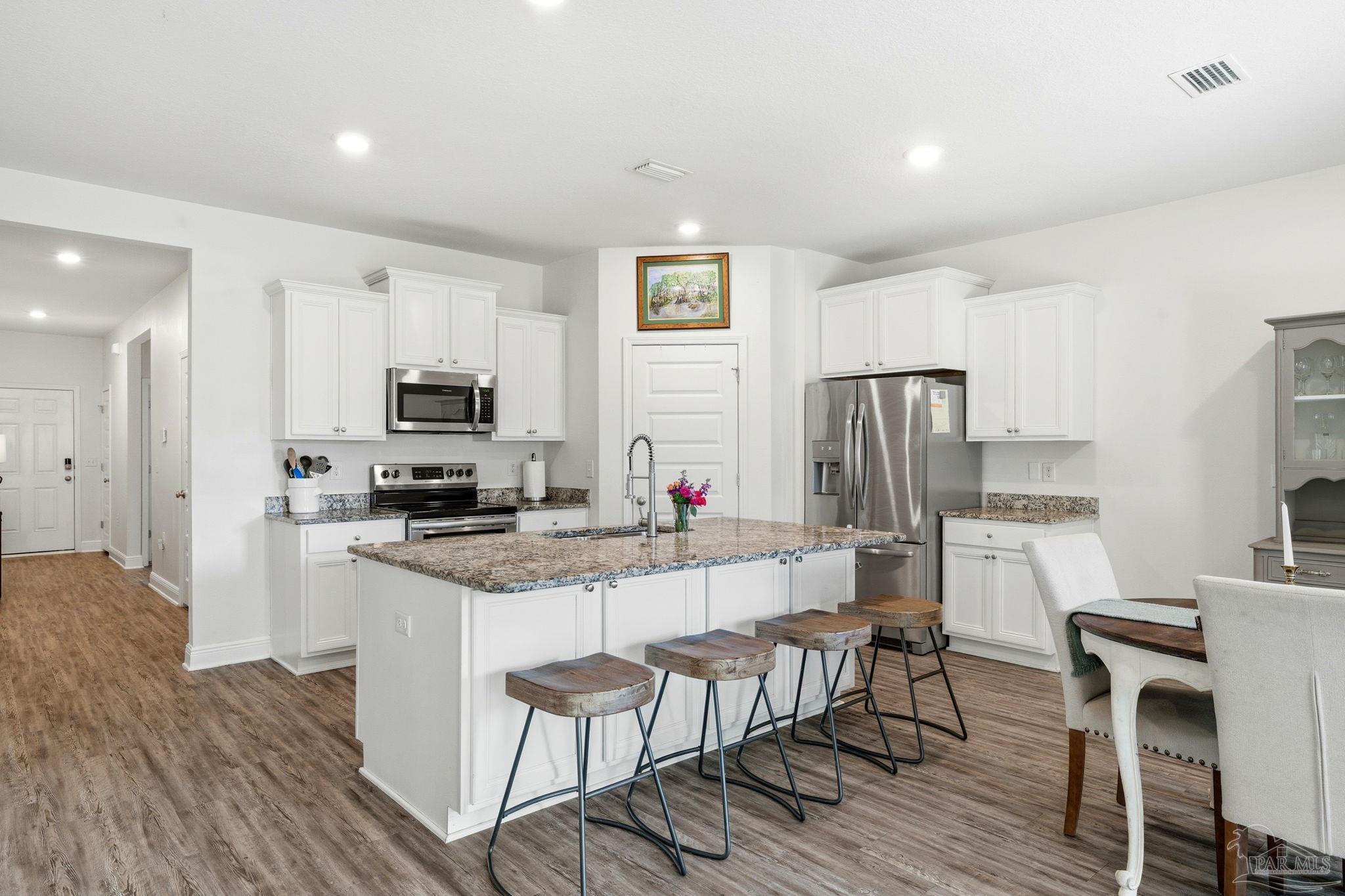 3797 Hawks Landing Circle Pace, FL 32571 - Photo 6 of 26 a kitchen with white cabinets and stainless steel appliances