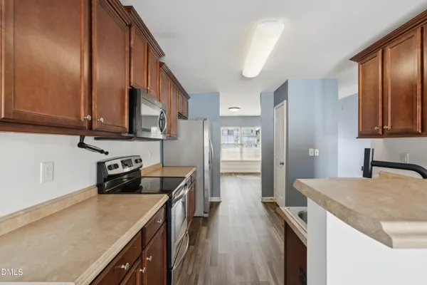 a kitchen with stainless steel appliances granite countertop a refrigerator a sink dishwasher a stove and white countertops with wooden floor