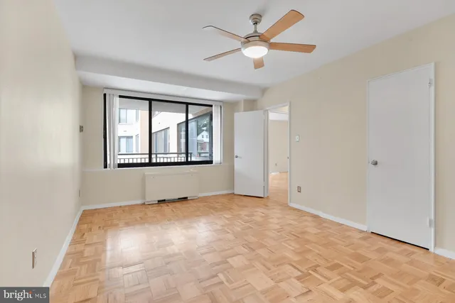 an empty room with chandelier fan and windows