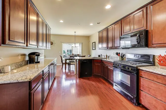 a kitchen with stainless steel appliances granite countertop wooden cabinets a stove top oven a sink and dishwasher
