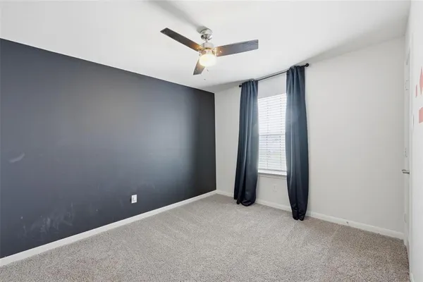 an empty room with a ceiling fan and window