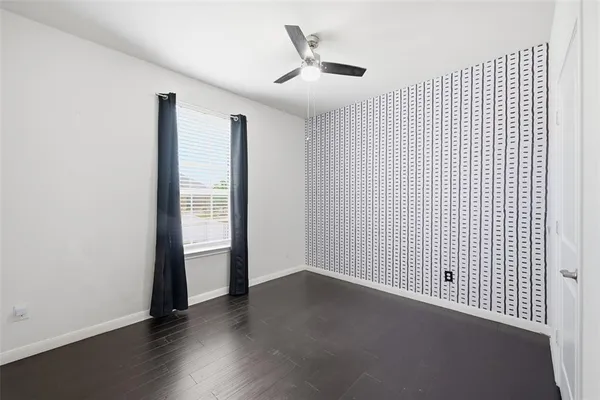 an empty room with wooden floor and a ceiling fan