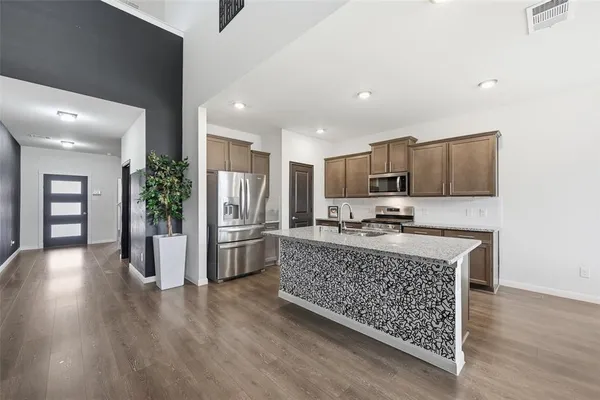 a kitchen with stainless steel appliances granite countertop a refrigerator oven a sink dishwasher and a stove with wooden floor