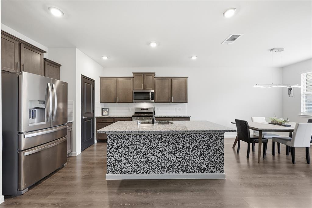 617 Range Drive Princeton, TX 75407 - Photo 4 of 26 a kitchen with stainless steel appliances granite countertop a stove top oven a sink a dining table and chairs