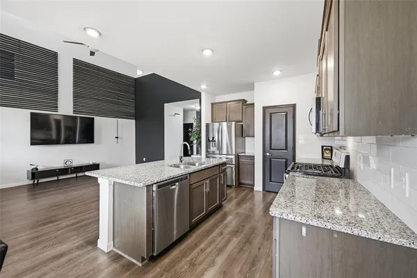 a large kitchen with stainless steel appliances granite countertop a stove a sink and a refrigerator