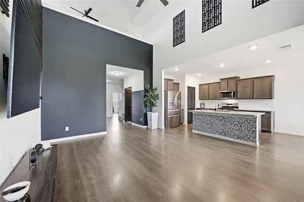a view of kitchen with kitchen island granite countertop a refrigerator oven a sink and white cabinets with wooden floor