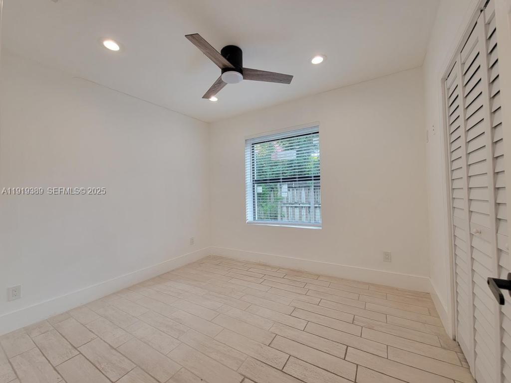 445 Southwest 3rd Street, Unit 1 Miami, FL 33130 - Photo 6 of 11 an empty room with a ceiling fan and windows