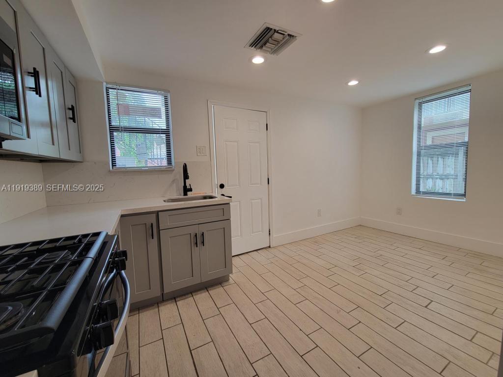 445 Southwest 3rd Street, Unit 1 Miami, FL 33130 - Photo 9 of 11 a kitchen with granite countertop a stove and a sink