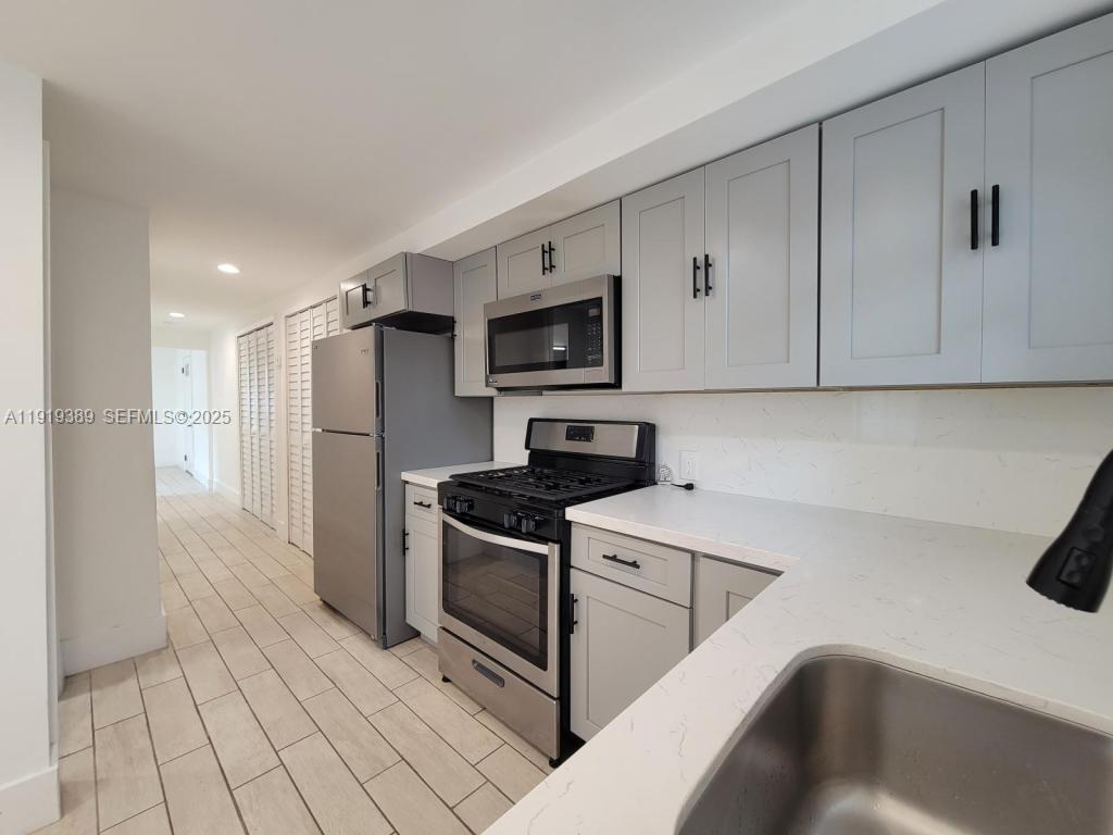 445 Southwest 3rd Street, Unit 1 Miami, FL 33130 - Photo 10 of 11 a kitchen with stainless steel appliances granite countertop a refrigerator and a stove top oven