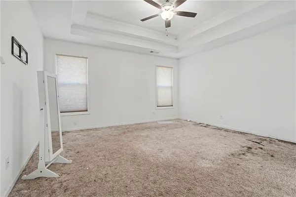 an empty room with a chandelier fan and windows