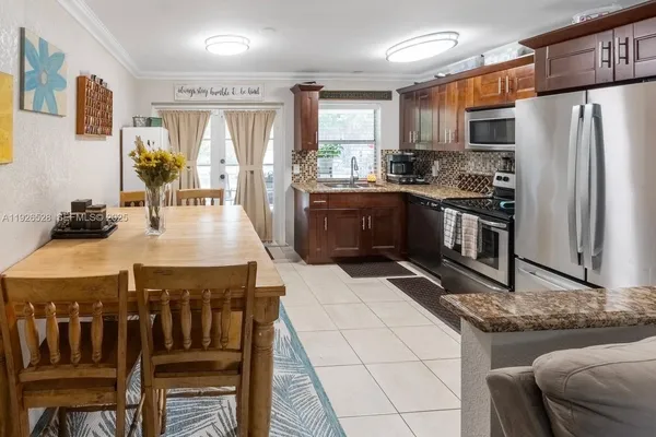a kitchen with stainless steel appliances granite countertop a stove a refrigerator a oven a sink a dining table and chairs with wooden floor