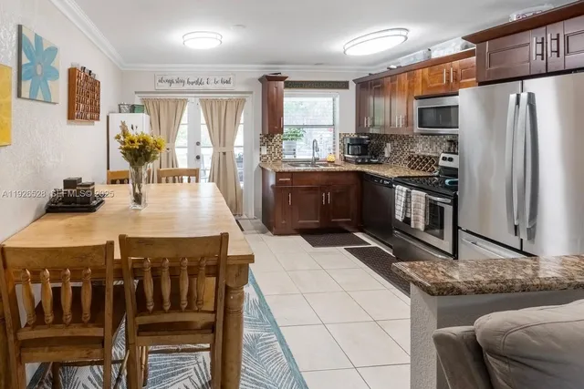 a kitchen with stainless steel appliances granite countertop a stove a refrigerator a oven a sink a dining table and chairs with wooden floor