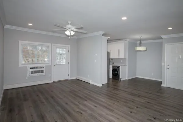 a view of an empty room with a window and wooden floor