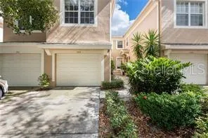 a view of a house with a large tree and a car parked in front of it