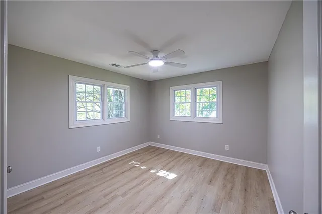 an empty room with wooden floor and windows