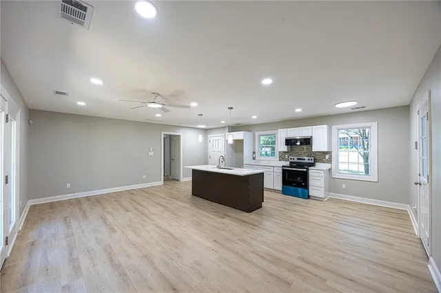 a view of kitchen with stainless steel appliances granite countertop a large counter top and wooden floors