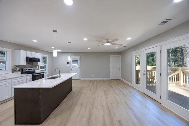 a large living room with stainless steel appliances granite countertop couches a flat screen tv and a large window