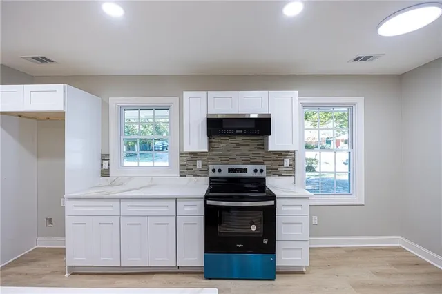a kitchen with stainless steel appliances white cabinets and a stove top oven