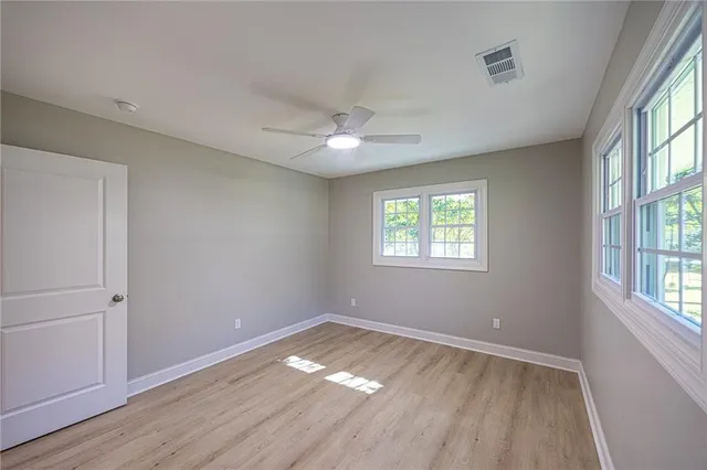 a view of empty room with wooden floor and fan