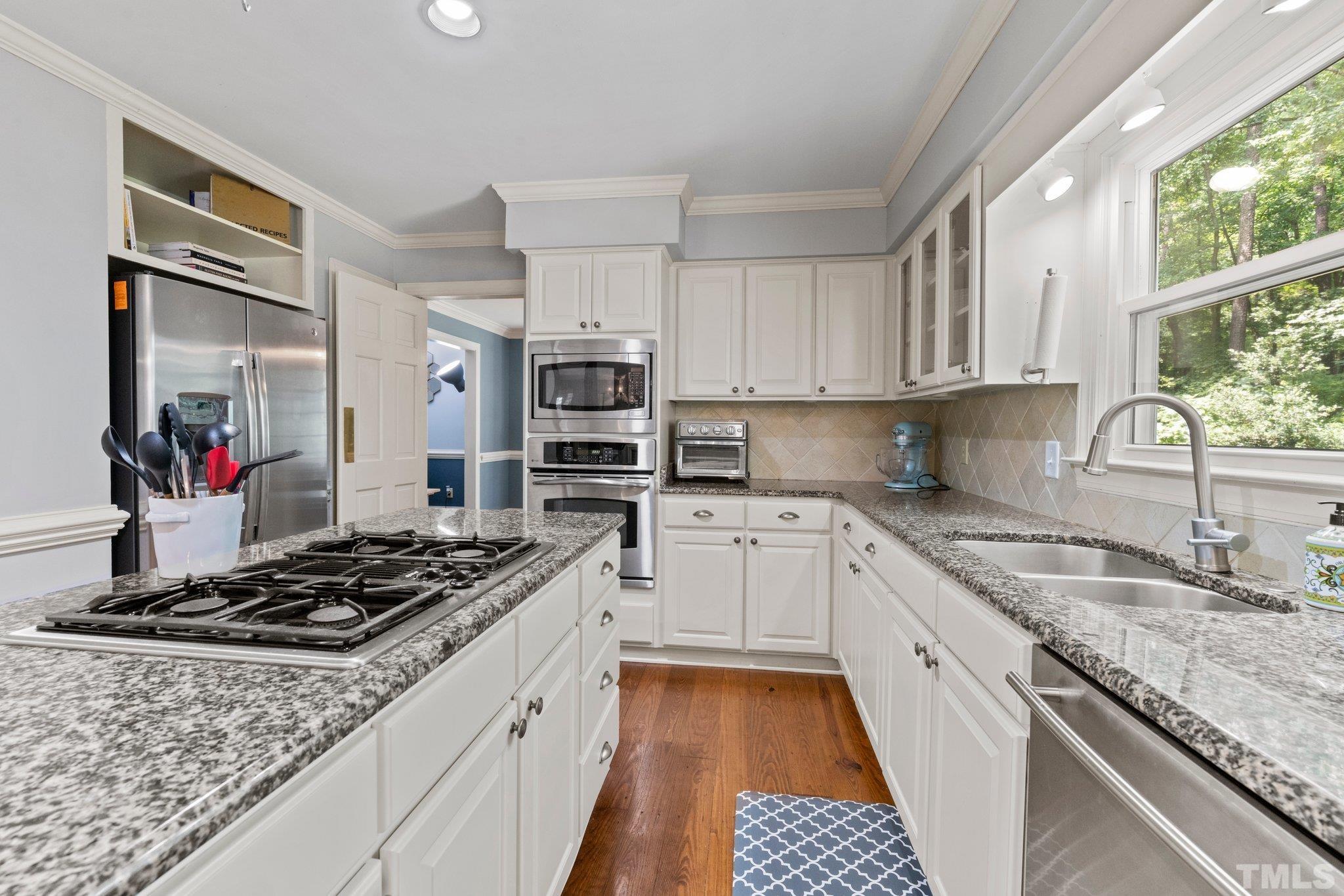 9301 Greenfield Drive Raleigh, NC 27615 - Photo 8 of 48 Kitchen features pantry, island, tile backsplash, and lots of storage including pull out shelves.