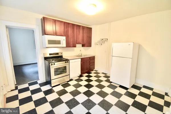 a kitchen with a checkered floor and steel appliances