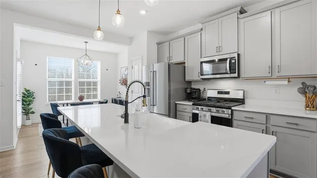 a kitchen with stainless steel appliances a stove a sink a microwave a dining table and chairs