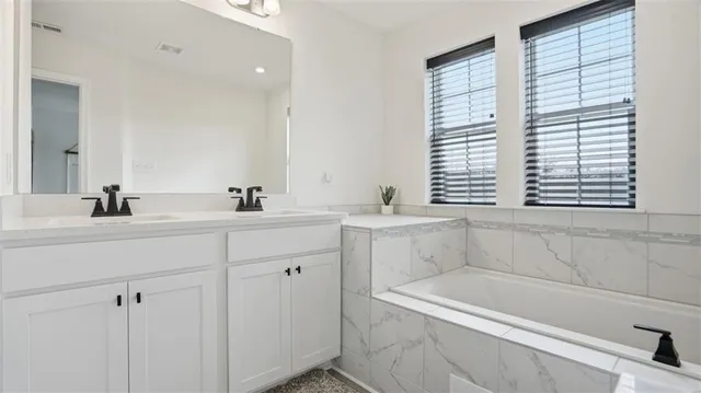 a bathroom with a bathtub a sink a vanity and a window