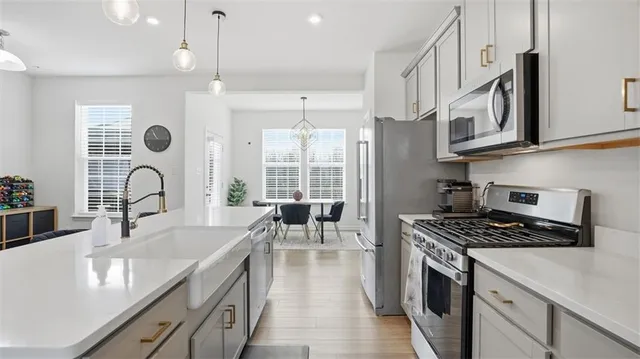 a kitchen with stainless steel appliances granite countertop a stove a sink dishwasher and white cabinets with wooden floor