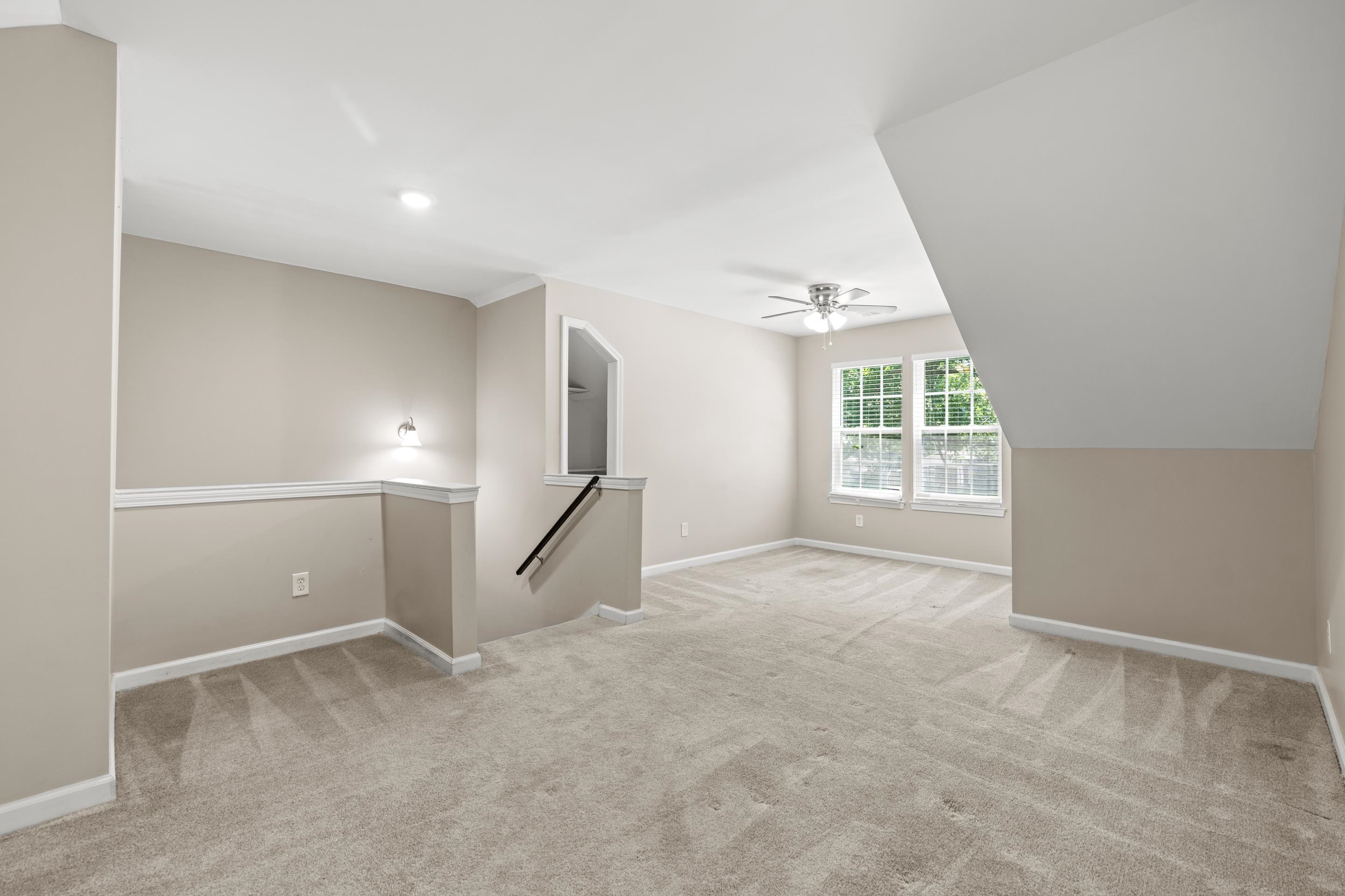 1255 Colonial Road Memphis, TN 38117 - Photo 24 of 30 Spacious carpeted room featuring a ceiling fan, dual windows, and an angled ceiling line