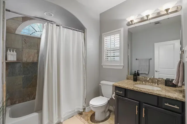 a bathroom with a granite countertop sink toilet and shower