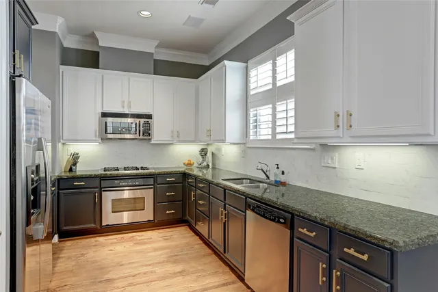 a kitchen with stainless steel appliances granite countertop white cabinets granite counter tops and a window