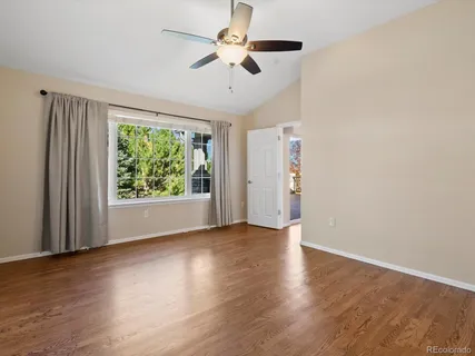 an empty room with wooden floor chandelier fan and windows