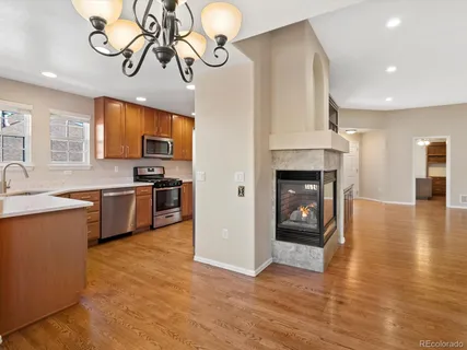 a kitchen with stainless steel appliances granite countertop a stove top oven a sink dishwasher and a fireplace with wooden floor