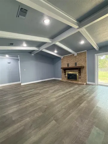 an empty room with wooden floor fireplace and windows