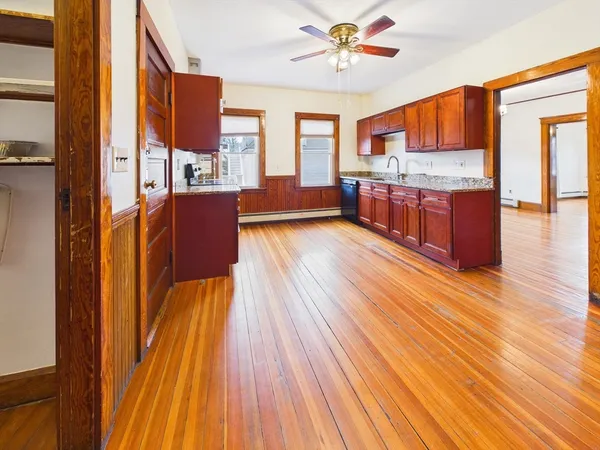 a open kitchen with stainless steel appliances granite countertop a refrigerator a stove top oven a chimney wooden floor and cabinets