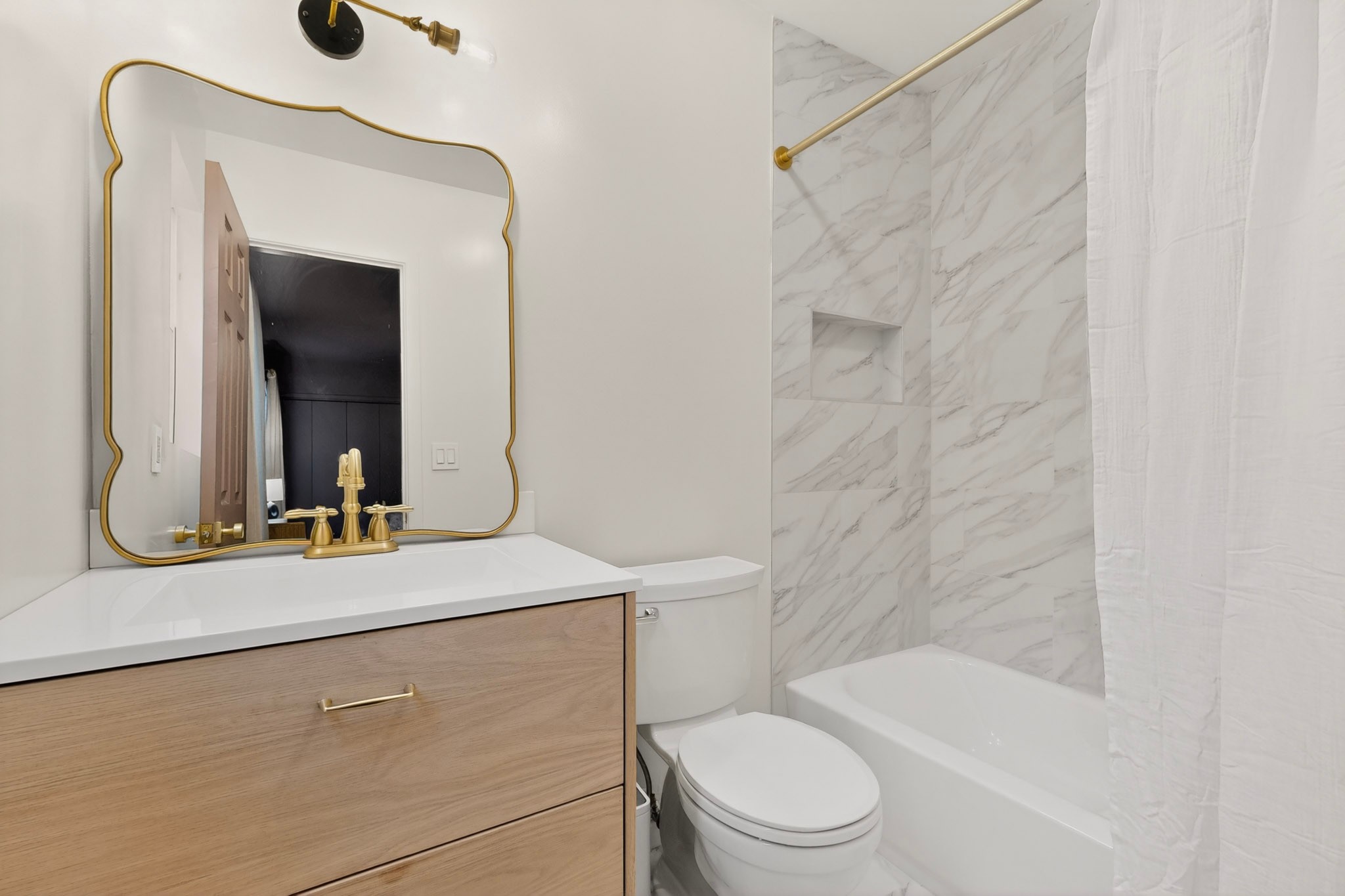 5541 Pine Place Austin, TX 78744 - Photo 20 of 33 Bathroom featuring a light wood-finish vanity with a white countertop, gold-finish faucet, and a decorative gold-frame mirror