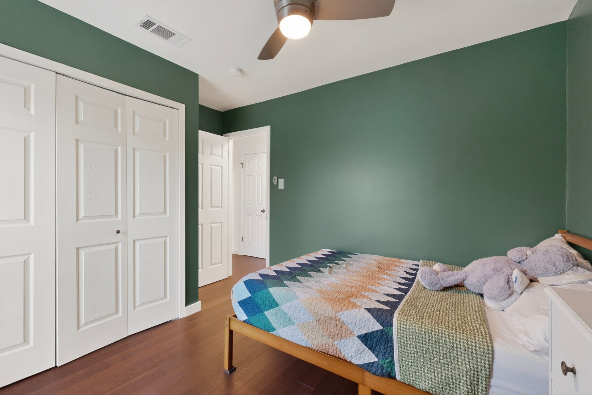 5541 Pine Place Austin, TX 78744 - Photo 23 of 33 Bedroom featuring wood-finish flooring, a ceiling fan with integrated lighting, and white bi-fold closet doors