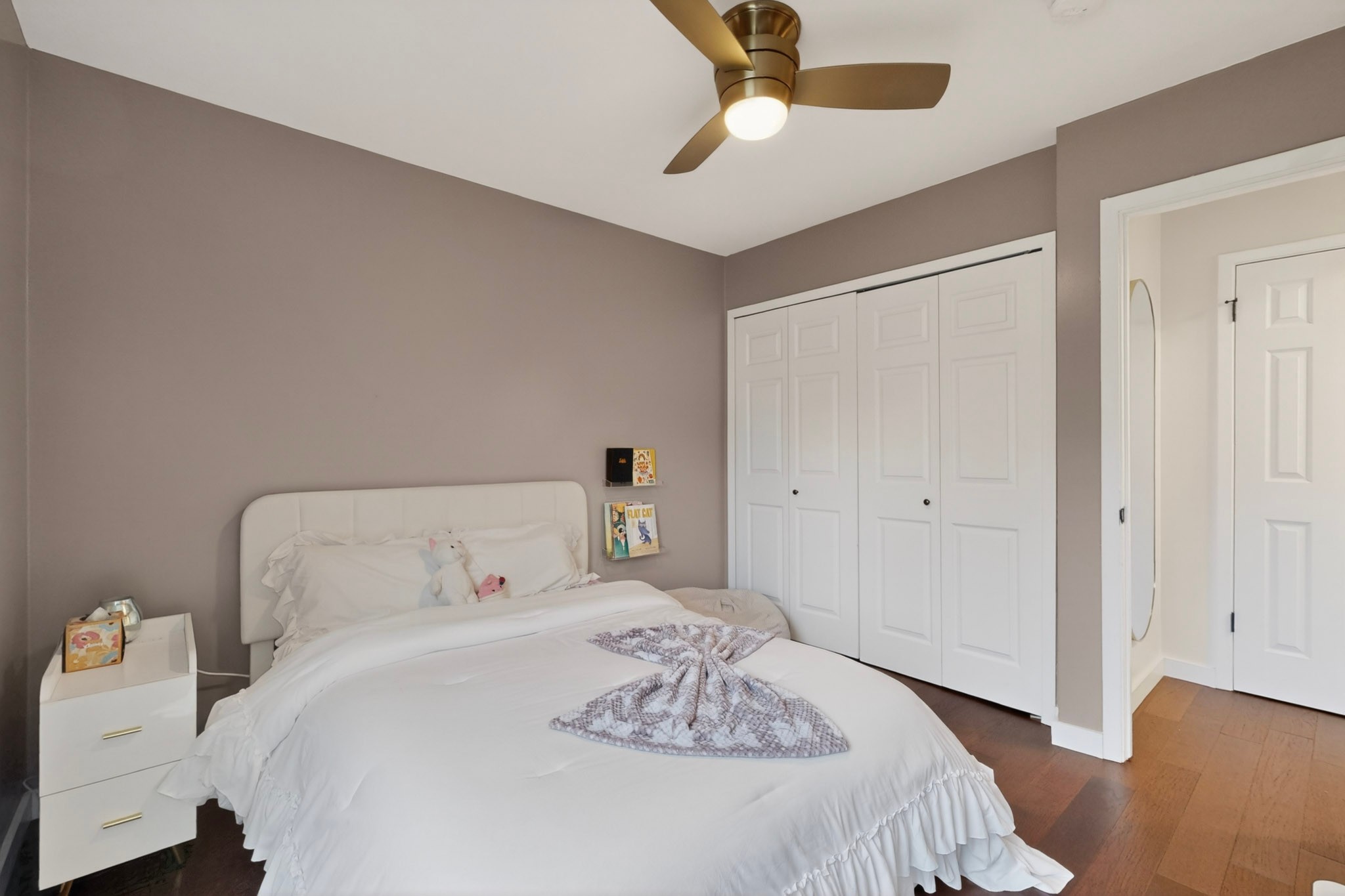5541 Pine Place Austin, TX 78744 - Photo 25 of 33 Bedroom featuring dark wood-finish flooring, a contemporary ceiling fan with integrated lighting, a spacious bi-fold closet, and neutral-toned walls
