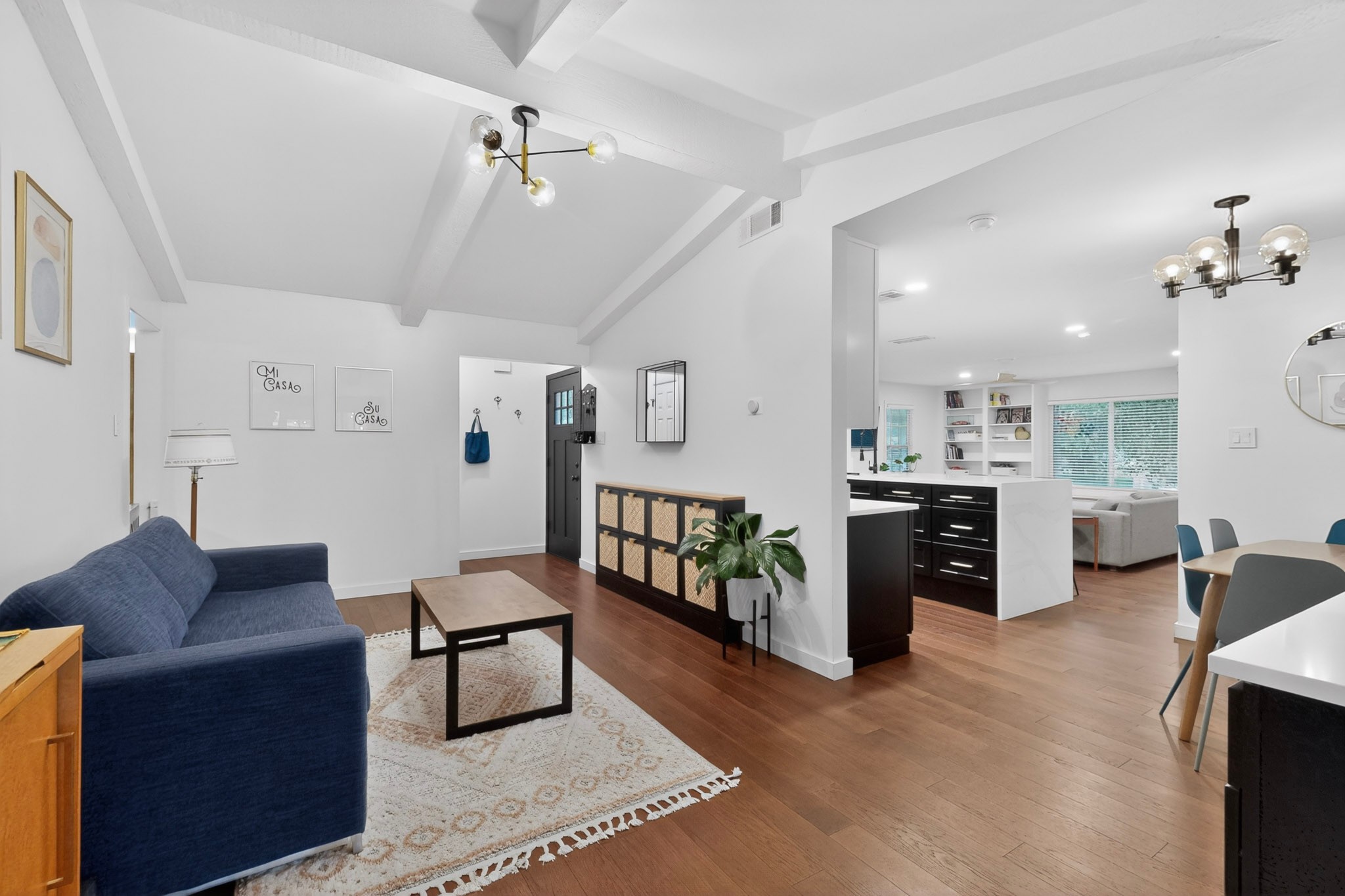 5541 Pine Place Austin, TX 78744 - Photo 6 of 33 Vaulted ceiling with exposed beams and a modern chandelier