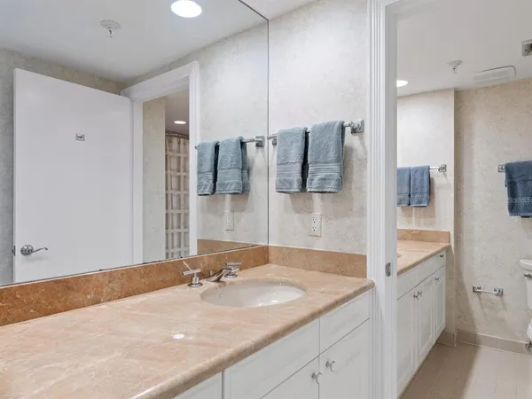 a bathroom with a granite countertop sink a large mirror and toilet
