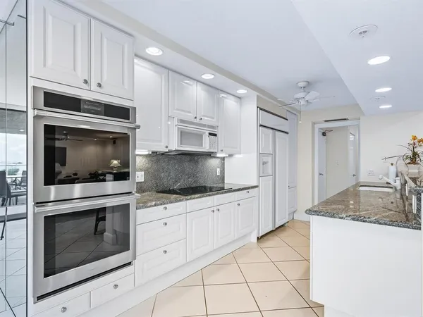a kitchen with granite countertop white cabinets stainless steel appliances and a sink