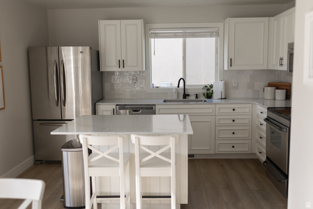1204 North 3020th Street West Provo, UT 84601 - Photo 13 of 35 Kitchen featuring white shaker-style cabinetry, stainless steel appliances, a center island with countertop seating, light-toned wood-finish flooring, and a window above the sink
