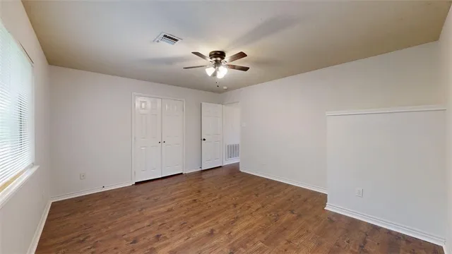 an empty room with chandelier fan and windows