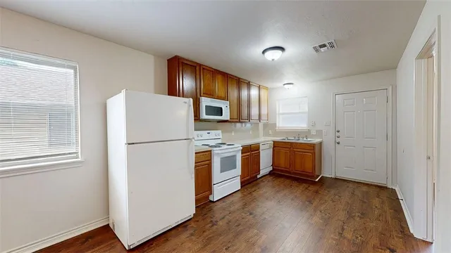 a kitchen with a refrigerator a stove top oven a sink and dishwasher with wooden floor