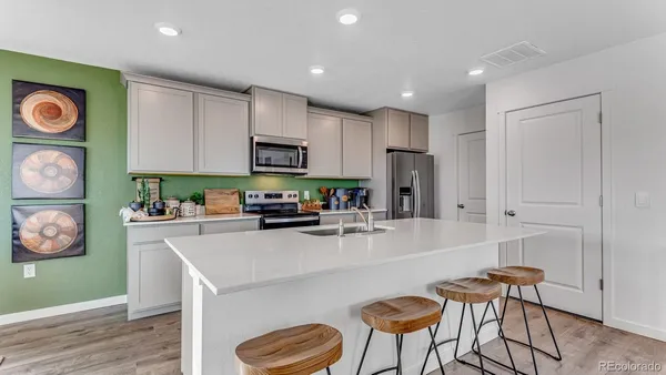 a kitchen with stainless steel appliances a microwave a stove a sink a refrigerator and cabinets