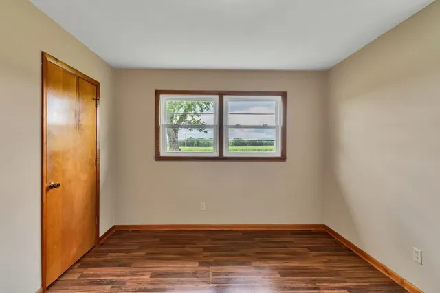 an empty room with wooden floor and a window